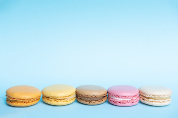 Top view of tasty colorful macaroons on blue background with copy space
