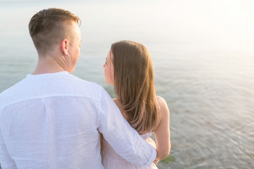 Summer couple embracing at sunset on beach. Romantic young couple enjoying sun, sunshine, romance and love by the sea. Closeup body foto
