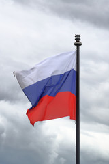 Tricolor Russian flag fluttering in the wind against a cloudy sky