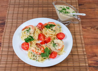 Cooked Spaghetti with shrims and tomatoes, sauce in sauce boat