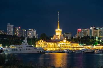 Obraz premium Sochi sea port. Evening illumination of the building. Attraction of the resort city. Parking for yachts and ships. City view.