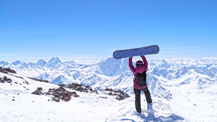 Girl with snowboard standing at the Caucasus Mountains,Elbrus