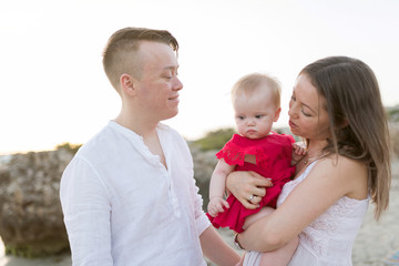 Young happy caucasian couple with little baby girl outdoors. Mother and father playing with toddler outdoors. Family, parenthood, childhood, happiness concept.