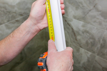 Man is measuring gypsum baseboard. Maintenance repair works renovation in the flat. Drywall panel.