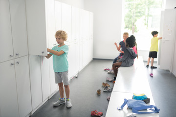 Children in a changing room preparing for sports. - obrazy, fototapety, plakaty