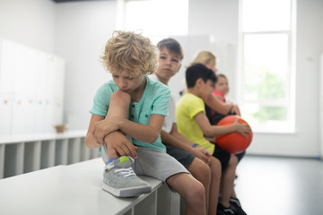 Sad pupil sitting in front of his classmates.