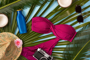 Beach theme on blue background. Beach accessories and palm leaves on blue background. Top view.