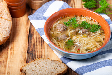 Homemade soup with noodles and meatballs on a wooden table. Traditional rural dinner