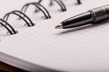 Fototapeta premium Opened notepad in a cage with an automatic plastic ballpoint pen close-up. toned