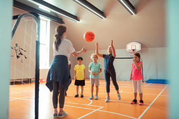 Obraz premium Children playing ball with their coach at sports class.