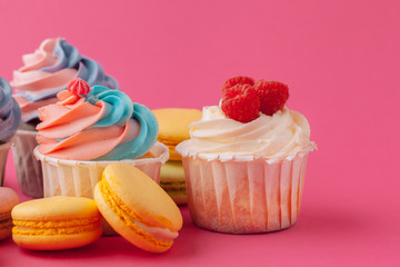 Tasty cupcakes sweets on pink background close up