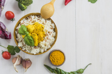 Elevated view of chicken fried rice and basil leaves with ingredients on white backdrop