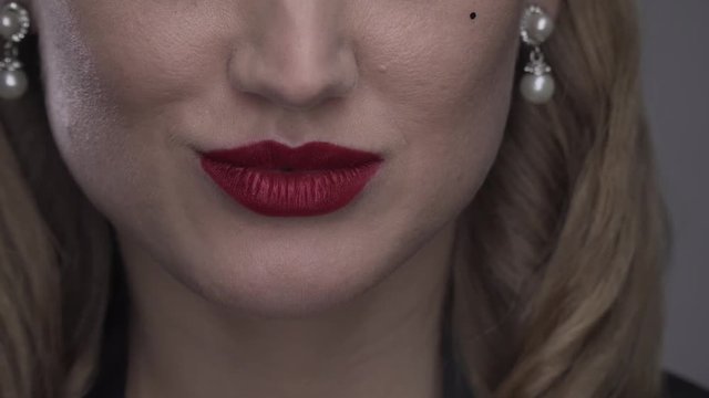 Young woman with red lipstick is biting her lip and smiling, close up, 4k