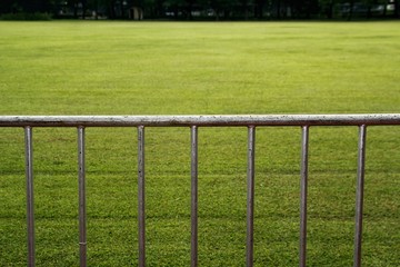Steel fence or barricade and a green grass field