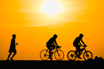 Silhouette man cycling on sunset background