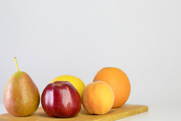 red apple, pear, lemon, orange, peach on white background, copy space