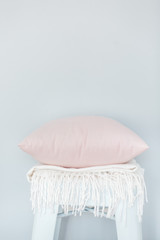 Fototapeta na wymiar Minimalistic skandinavian picture of a light pink pillow and a white plaid on the chair near a pale blue wall