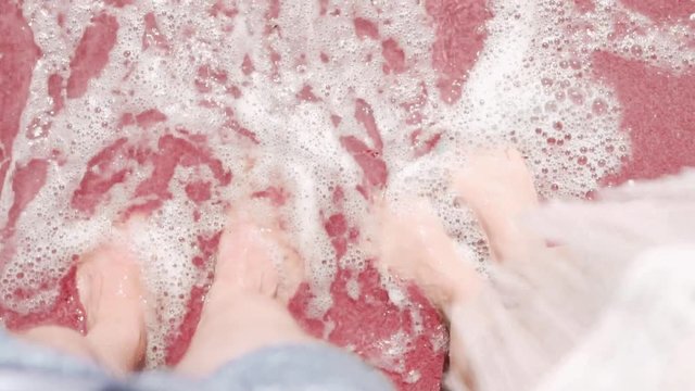 The waves wash the feet of a man and the feet of a woman in love with a couple on the bard dark red sand by the sea of the ocean, relaxation, enjoyment of rest, rest, tourist trip, travel, close-up, s