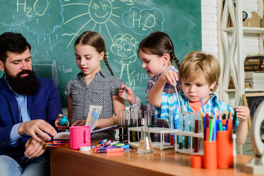 students doing science experiments with microscope in lab. school kids scientist studying science. happy children & teacher. back to school. Little kids learning chemistry in school laboratory