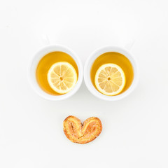 Lemon tea cups with palmiers pastry on white background