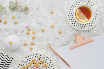 Antique pen on clipboard with candies and ginger lemon tea cup on tablecloth