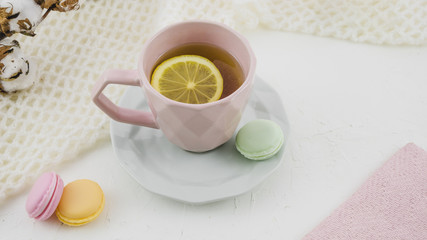 Obraz na płótnie Canvas Herbal lemon tea with macaroons on white backdrop