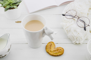 Palmiers or elephant ear puff pastry cookie with porcelain white tea cup on wooden desk