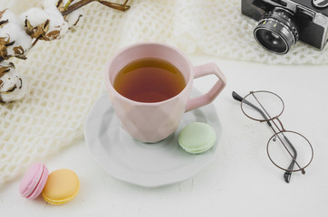 Eyeglasses; camera; cotton twig with herbal tea cup and macaroons on white backdrop