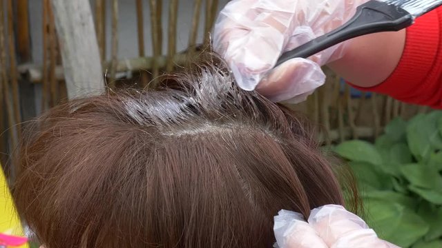 woman applying hair dye on her head with a brush