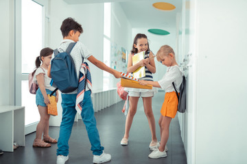 Rude dark-haired boy taking book away from little girl