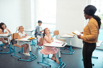 Obraz premium Cute girl in pink dress raising hand while answering the question