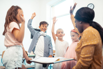 Children and teacher raising their hands while having fun together