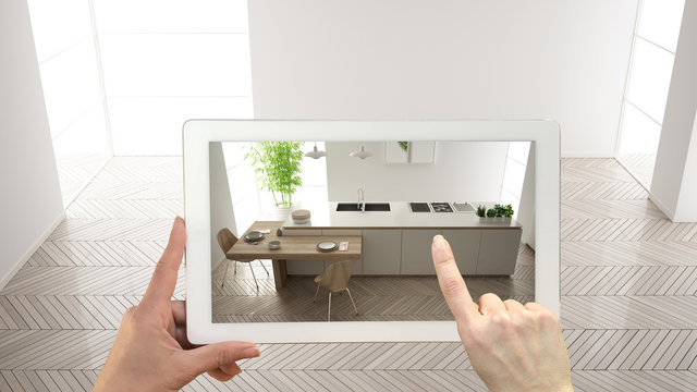 Augmented reality concept. Hand holding tablet with AR application used to simulate furniture and design products in empty interior with parquet floor, modern white kitchen, top view