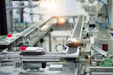 Focus on robot arm's gripper. Industry 4.0 concept; artificial intelligence in smart factory. Robot picks up the product from automated car on the manufacturing line. Selective focus.
