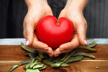 Tomato in the shape of a heart in female hands. Healthy food.