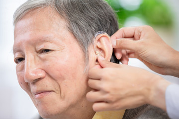 Obraz premium Doctor help patient wear audiphone