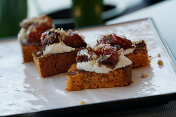 Bruschetta, toasted slices of bread with feta cheese, dried tomatoes, on a white plate.