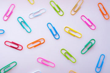 Bright colourful paper clips  laying in disorger on a pink background