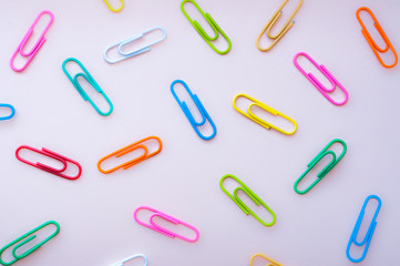 Bright colourful paper clips  laying in disorger on a pink background