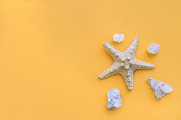 Fototapeta na wymiar Starfish and small sea stones on an yellow background. Sea summer theme