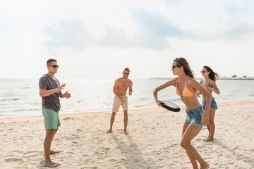 Group of friends playing at the beach on summer vacations