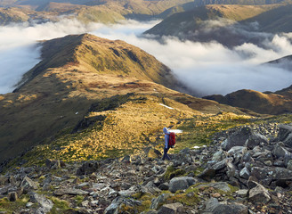 A hiker descending Hart Crag towards Hartsop Above How near Patterdale in the English Lake District.