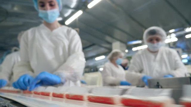 Women take food from a factory conveyor, packing.