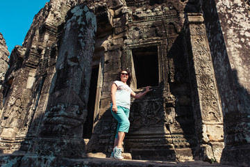 Adult woman tourist posing beside ancient Khmer ruins in Cambodia, Angkor Wat, Siem Reap
