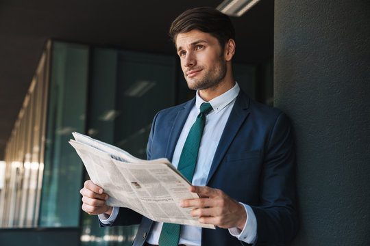 Photo of confident businessman reading newspaper while standing outside job center