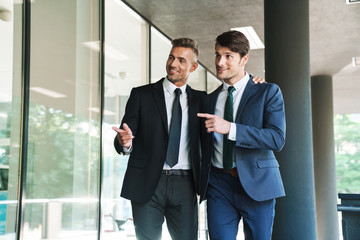 Portrait of two smiling businessmen partners walking outside job center during working meeting