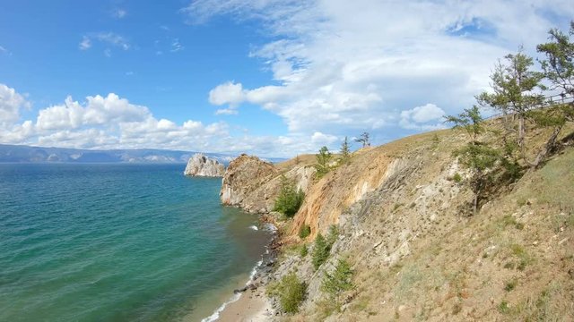 Aerial view of a girl sitting on a steep bank and drawing. Beautiful landscape, lake Baikal, 4K