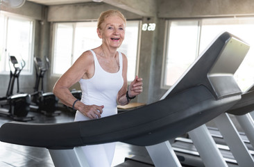 Fototapeta na wymiar Senior women exercise jogging at gym fitness smiling and happy. elderly healthy lifestyle.
