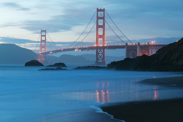 Classic panoramic view of famous Golden Gate Bridge seen from scenic Baker Beach in beautiful golden evening light on adusk with blue sky and clouds in summer, San Francisco, California, USA