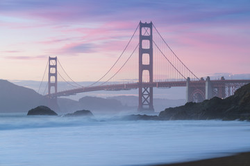 Classic panoramic view of famous Golden Gate Bridge seen from scenic Baker Beach in beautiful golden evening light on sunset with blue sky and clouds in summer, San Francisco, California, USA